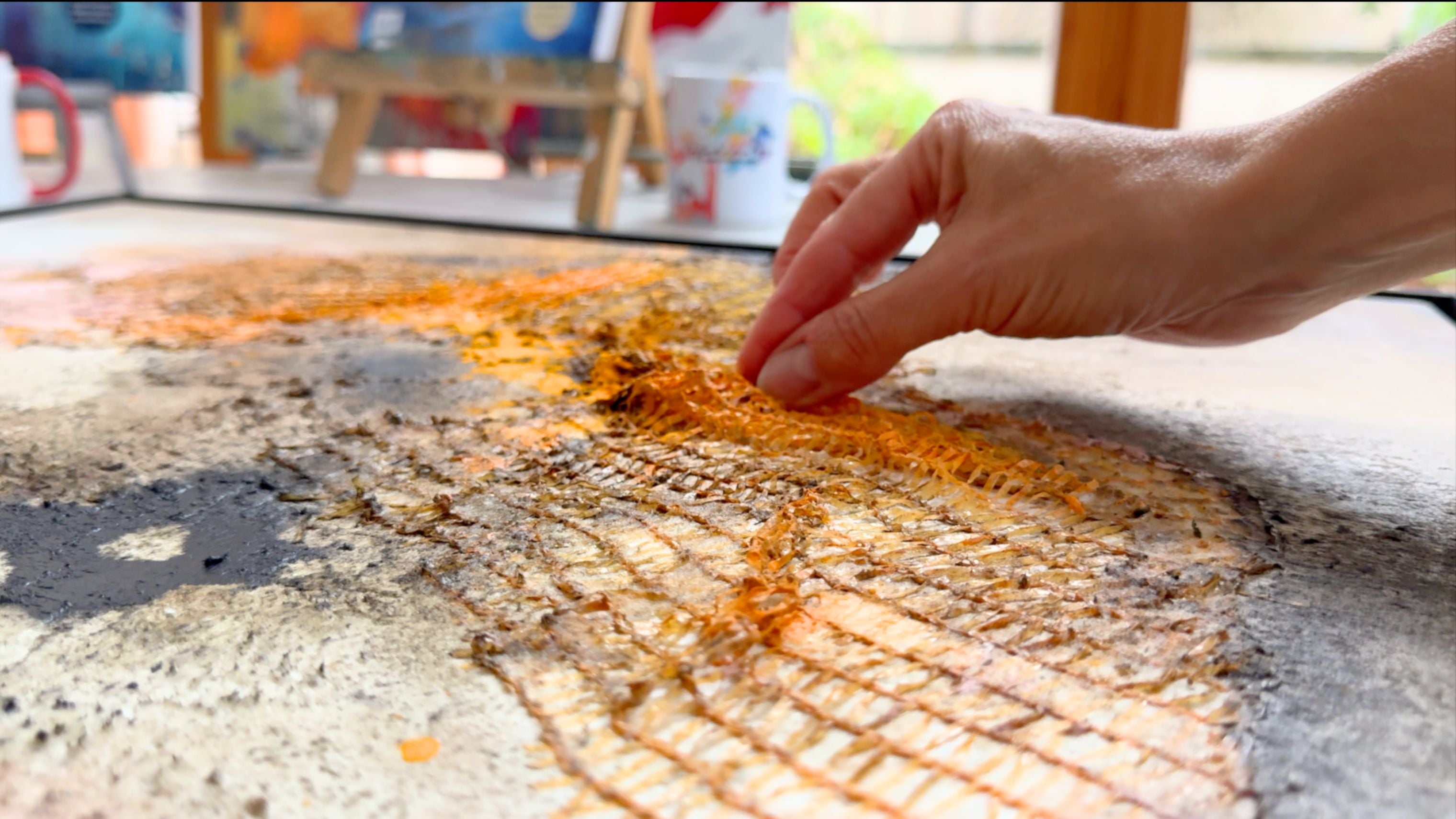 Abstraktes Malen mit orangefarbenem Kunststoffnetz und fließender Acrylfarbe