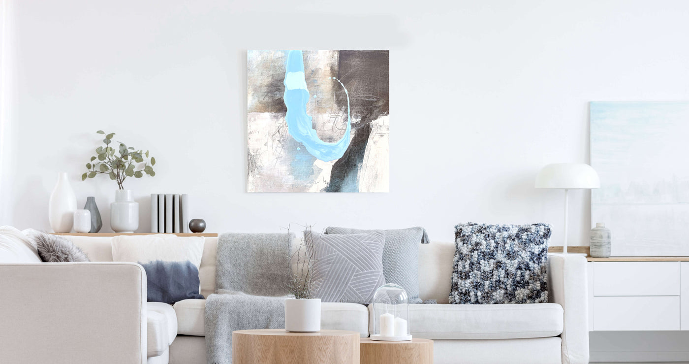 Original Kunstwerk von Petra Thoelken hängt über einem Sofa. Es ist in natürlichen Farbtönen. Sand, Grau und Blau überwiegen.